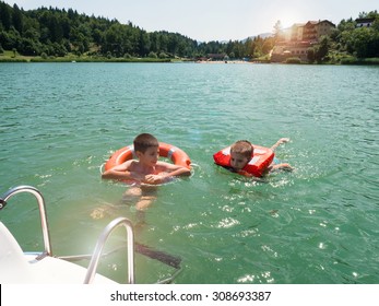 Young Kids Swimming In Lavarone Lake With Life Buoy. Trentino Alto Adige Region, Italy. Filtered Image Instagram Style.