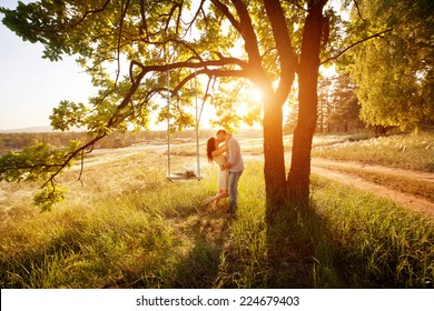 Young kissing couple under big tree with swing at sunset - Powered by Shutterstock