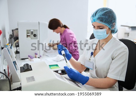Young lab worker performing a biochemical analysis in latex gloves