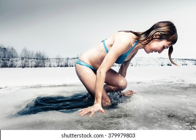 Young lady comes out from the ice hole after recreational swimming