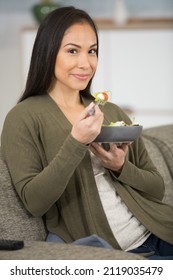 Young Lady Eating A Salad Sat On The Sofa