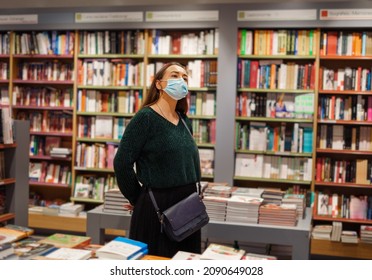 Young Lady In Face Mask Stands In Bookstore During Covid19 Outbreak