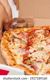 Young Lady Hand Grabbing A Slice Of All Meat Pizza 