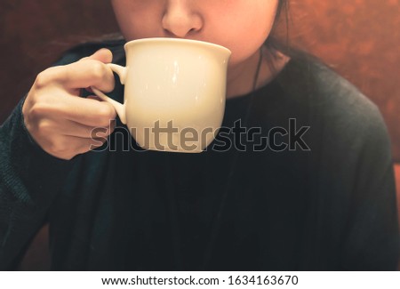Young lady hand holding a coffee cup  at the cafe