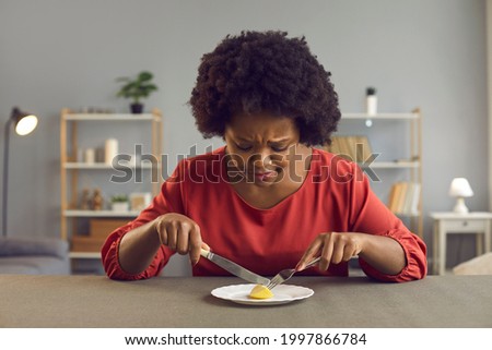Young lady having tiny serving for lunch. Sad black woman who's sticking to strict diet eating nothing more than ridiculous portion of one little piece of apple. Nourishment and weight loss concept
