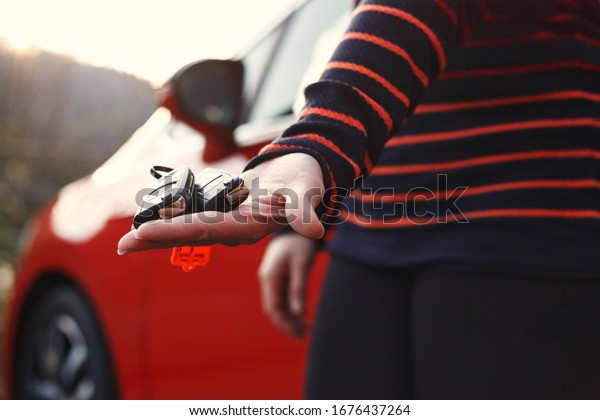 Young lady holding and showing car keys in hand.\
Standing in front of the\
car.