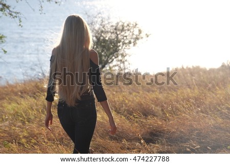 a young lady with long hair walking away in the wild steppe, going towards a better future