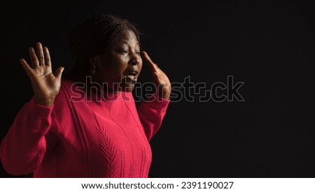 Young lady making I dont know gesture, lifting her shoulders implying confusion and uncertainty. Being ignorant and insecure with perplexed and bewildered reaction in isolated black background.