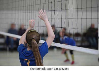 A young lady is at the net as she competes in a youth volleyball match - Powered by Shutterstock