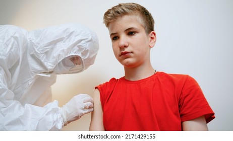 Young Lady Nurse Giving Covid-19 Or Monkeypox Or Flu Antivirus Vaccine Shot To Teen Male Patient That Protection From Virus Disease At Health Clinic Or Hospital Office. Vaccination Concept.