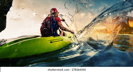 Young lady paddling hard the kayak with lots of splashes