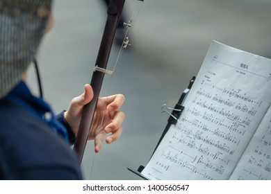 A young lady playing a Chinese violin (Erh-hu) on the street