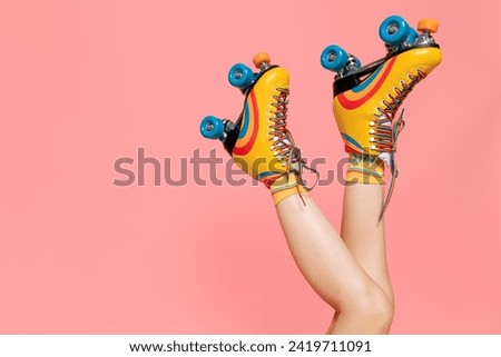 A young lady with rainbow quad rollers on pink background