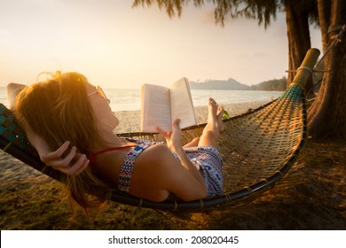 Young lady reading a book in hammock on a beach at sunset - Powered by Shutterstock