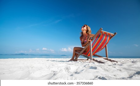 Young lady relaxing in the chair on a tropical beach with white sand