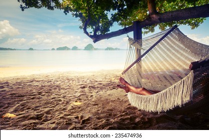 Young lady relaxing in the hammock on the sandy beach with view on remote tropical islands - Powered by Shutterstock