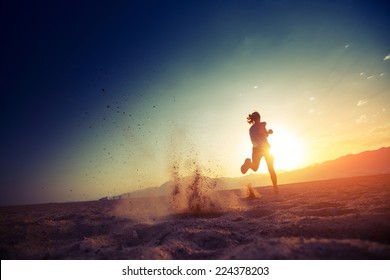 Jeune femme courant dans le désert au coucher du soleil