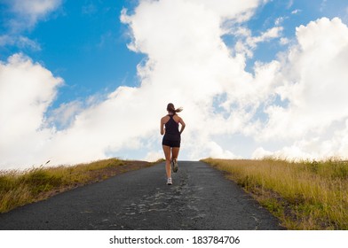 Young lady running on a road up hill.