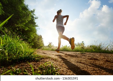 Young lady running on a rural road during sunset - Shutterstock ID 136301591