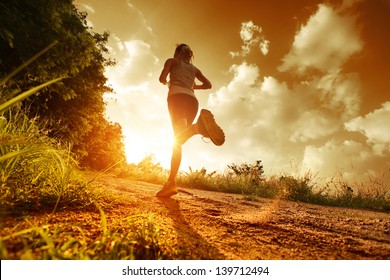 Young lady running on a rural road during sunset - Powered by Shutterstock