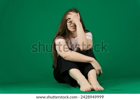 A young lady shaking her head in fury and crying against a green background. Medium shot. High quality photo