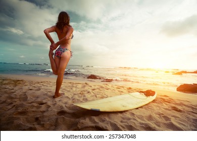 Young lady stretching on the beach before surfing - Powered by Shutterstock