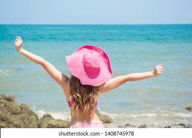 Young lady sunbathing on a beach. Beautiful woman posing at the summer sand beach. Outdoor summer portrait of pretty sport style woman in pink bikini and Winged hat . Beautiful fit tan girl. Sexy.