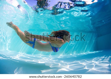 Young lady swimming underwater in the pool