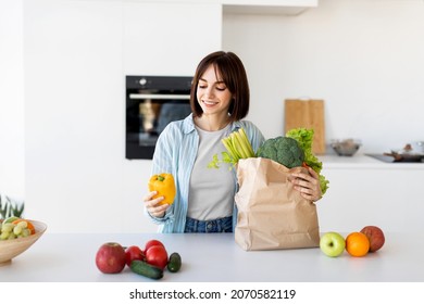 Young lady unpacking grocery bag after shopping, putting vegetables on table in kitchen interior at home, copy spsce. Dinner preparation and household leisure concept - Powered by Shutterstock