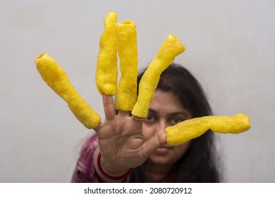 A young lady using fryums as her finger nail to recall her childhood days. Selective focus on fryums.