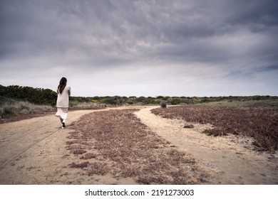 Young Lady Walking At The Beach During A Cloudy Day