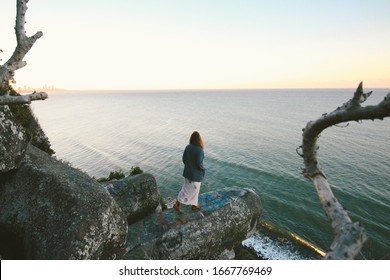 Young Lady Walks Stand On Look Out Of Cliff Edge To Beach Along Coastline Overlooking Beach And Sunset During Dusk