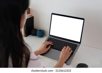 Young Lady Working On Her Laptop With White Working Desk Background. Black Mockup Laptop Screen. Black Copy Space For Advertising Text Message. Back View Of Business Women Hand Using Laptop