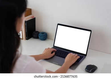 Young Lady Working On Her Laptop With White Working Desk Background. Black Mockup Laptop Screen. Black Copy Space For Advertising Text Message. Back View Of Business Women Hand Using Laptop