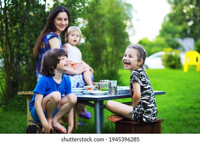 A Young Large Family At A Picnic On A Summer Morning. A Beautiful Mother With Children Is Having Breakfast In The Park.