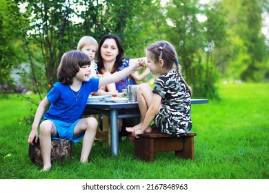 A Young Large Family At A Picnic On A Summer Morning. A Beautiful Mother With Children Is Having Breakfast In The Park.