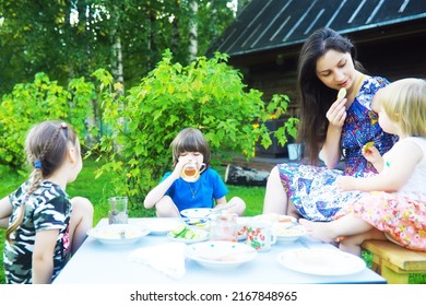 A Young Large Family At A Picnic On A Summer Morning. A Beautiful Mother With Children Is Having Breakfast In The Park.