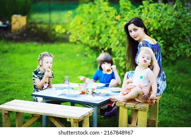 A Young Large Family At A Picnic On A Summer Morning. A Beautiful Mother With Children Is Having Breakfast In The Park.