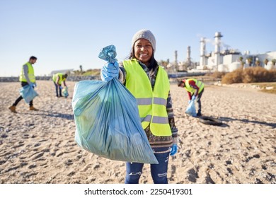 Young latin activist looking at camera holding a garbage bag trash. Group of cleanup volunteers cleaning up waste in nature on sunny day. Concept of environmental protection. - Powered by Shutterstock