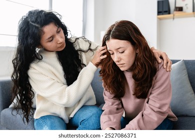 Young latin american girl comforting her upset female friend after breaking up her relationship with boyfriend sitting together on sofa at home. - Powered by Shutterstock