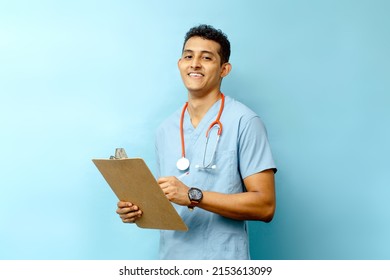 Young Latin American Male Assistant Holding A Medical Chart And A Pen.