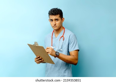 Young Latin American Male Assistant Holding A Medical Chart And A Pen.