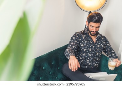 Young Latin American Man Working On His Tablet With A Warm Cup Of Coffee In The Office, Studio Shot. High Quality Photo