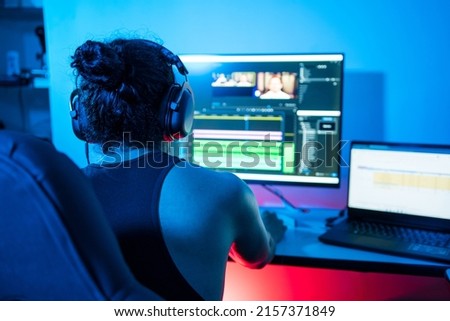 Young Latin American using the computer at night, editing videos and exporting audiovisual pieces. Person using a computer to create content from home. video editor, pc gamer