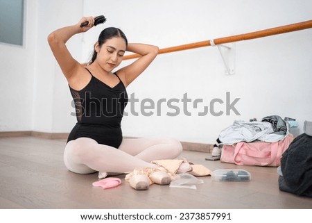 young latin ballet dancer preparing before class combing her hair; hispanic ballerina getting ready putting on pointe shoes