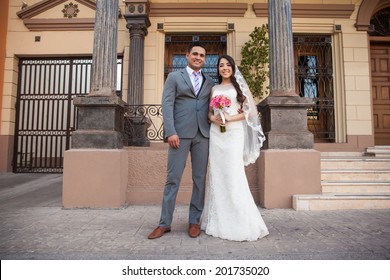 Young Latin Bride And Groom Standing Together Outside A Courthouse On Their Wedding Day