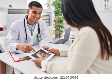 Young latin couple doctor and patient looking baby ecography at clinic - Shutterstock ID 2260419393