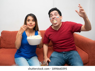 Young Latin Couple Eating Pop Corn And Watching Tv. Latin Fans Watching A Game