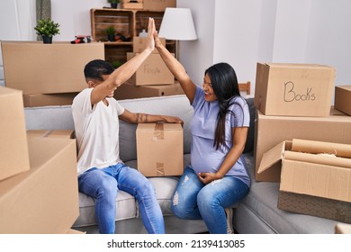 Young Latin Couple Expecting Baby High Five Raised Up Hands At New Home