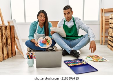 Young Latin Couple Having Online Paint Class At Art Studio Thinking Attitude And Sober Expression Looking Self Confident 